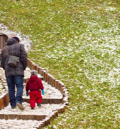father and son walking in winter park, they climb the stairs, they were in warm winter jackets, it's cold outsideの写真素材