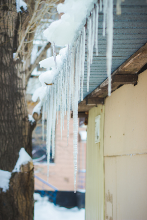 in winter the water freezes under the eaves of buildings and formed iciclesの写真素材