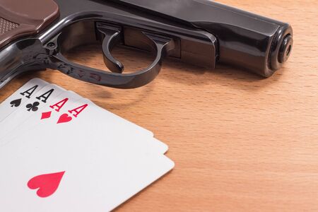 black pistol and a great poker hand of cards on a wooden background