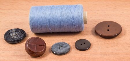 spool of thread and a variety of buttons on a wooden backgroundの写真素材