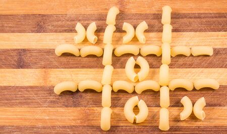 Tic Tac Toe game laid out on wooden background pastaの写真素材