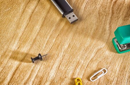 Office accessories on a wooden background, stapler, paper clips and a flash drive for storing informationの写真素材