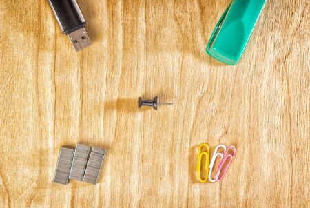 Office accessories on a wooden background, stapler, paper clips and a flash drive for storing...