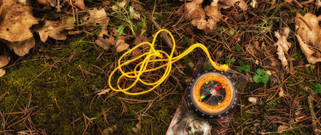 A compass on the ground in the forest is a device for a landmark. It shows the direction, its arrow always points north, around dry leaves, moss and plantsの写真素材