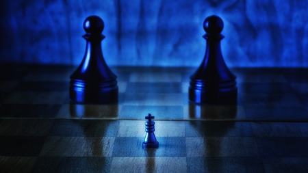 A small black chess king and big pawn servants, chess is an exciting and popular game all over the world, actions take place on such a wooden boardの写真素材