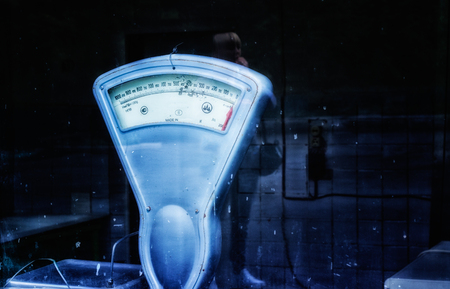 Atmosphere of soviet times vintage scales view behind a glass reflection of a blond young woman with a handbagの写真素材