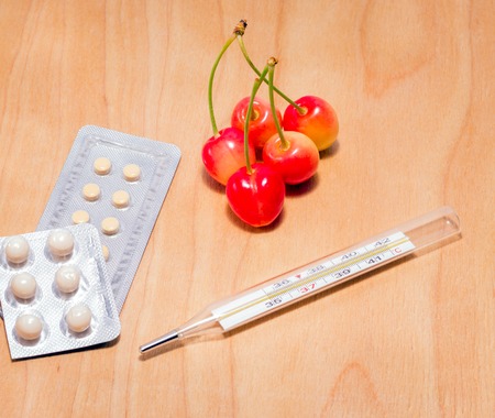 Objects for health care on a wooden background thermometer for measuring body temperature, tablets and berriesの写真素材