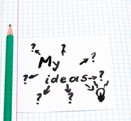 A sheet with an inscription my ideas and a simple pencil arrow pointing at dubious variants with question marks and only one leading to the idea that the painted lamp symbolizesの写真素材