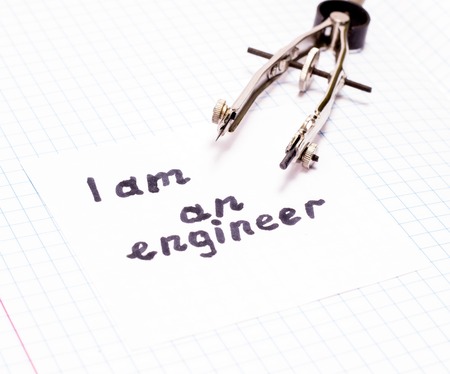 sheet of paper with the inscription I am an engineer and a compass tool for drawing circles on an open notebookの写真素材