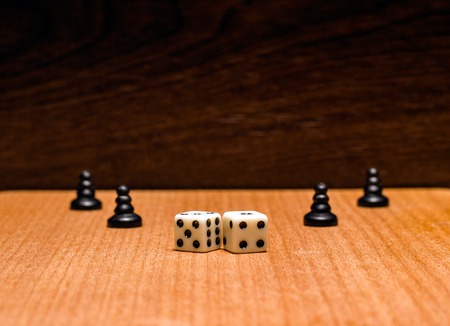 Black pawns and dice on a wooden background are popular objects for board games of logical and developingの写真素材