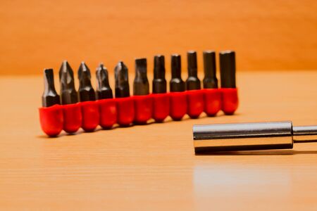 Devices for mounting and dismantling on a wooden background a metal tip of a screwdriver and various nozzles of different pointsの写真素材