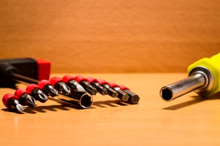 Two screwdrivers and metal nozzles on them on a wooden background tools for mounting and dismantling and also repairingの写真素材