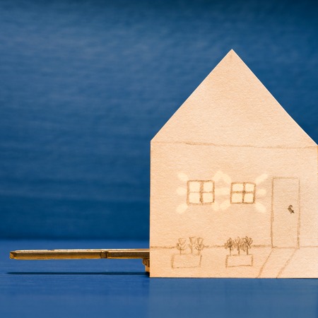 Paper house and the light of its windows on a blue backgroundの写真素材