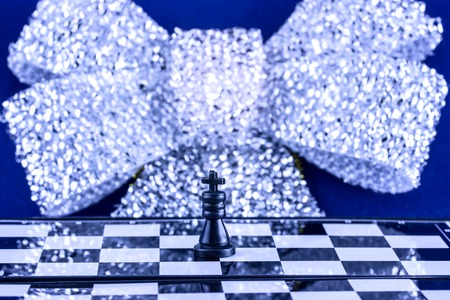 king on a chessboard on a background of a brilliant bow festive atmosphere of Christmas bright and beautifulの写真素材