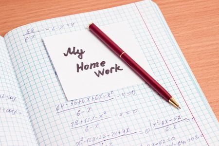pen and a piece of paper with the inscription my homework lay on an open notebook on mathematicsの写真素材
