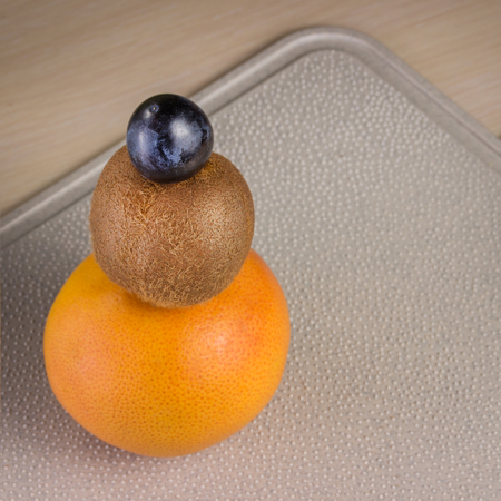pyramid of ripe and fresh fruits on a plastic kitchen board with pimples grapefruit kiwi and blue grapesの写真素材