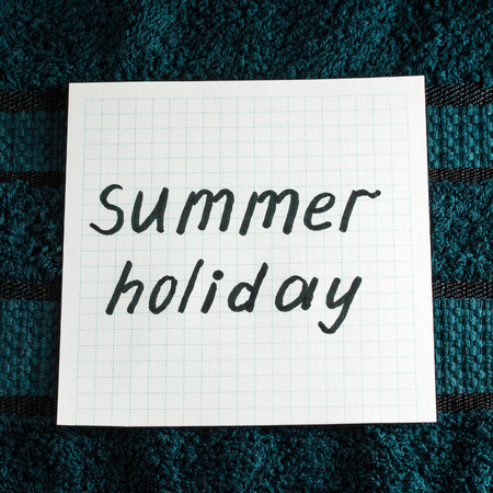 inscription summer holiday in English on a sheet of notebookの写真素材