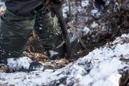 digging the earth in winter a warm boot presses on the metal