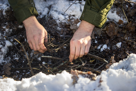 Two hands over a small fire in the winter on the nature corrects thin sticks to unleash a flameの写真素材