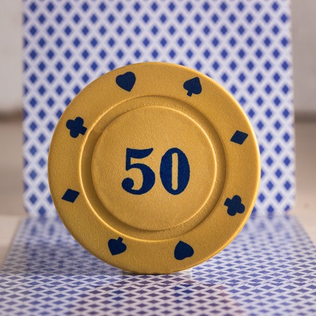poker chip on a blurry background of the back of the playing cards is a bright object for the most popular and gambling cardsの写真素材