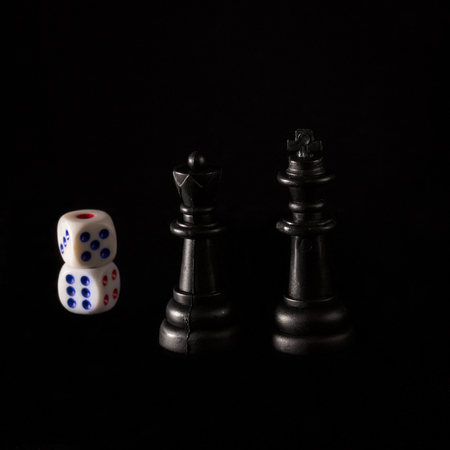 black king and queen next to dice on a dark background concept of popular board gamesの写真素材