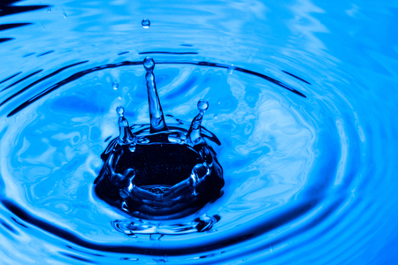 bright drops and a spectacular splash on the blue water surface concept of nature delightful abstract closeupの写真素材