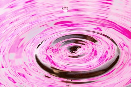 small drop of flying out of the water in which the violet paint is reflected beautiful abstractionの写真素材