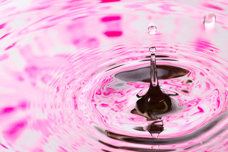 high shiny drop closeup on a background of water in which a violet paint is reflected beautiful abstractionの写真素材