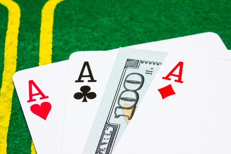 three aces and one hundred dollars on a green poker canvas closeup concept of winnings and casinosの写真素材
