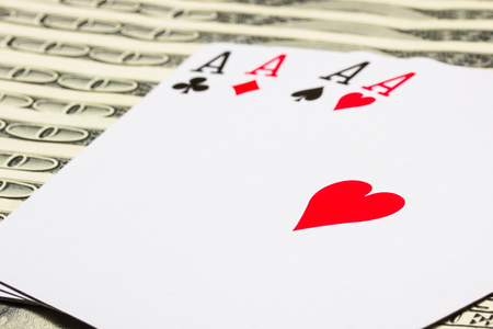 four aces closeup on a blurred background of hundred dollar bills concept of winning and gambling