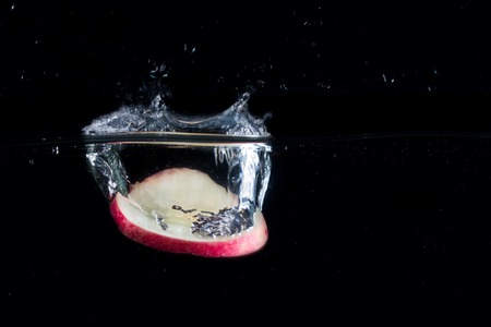 piece of apple fallen into the water on a dark background formed a spectacular splash on the surface...