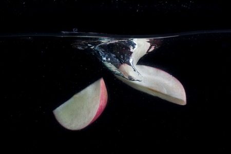 beautiful splash under water from fallen pieces of fresh apple concept of food and fruitの写真素材