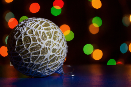 christmas toy with sparkles in the shape of a ball on a background of blurred lights garlands concept of the new yearの写真素材