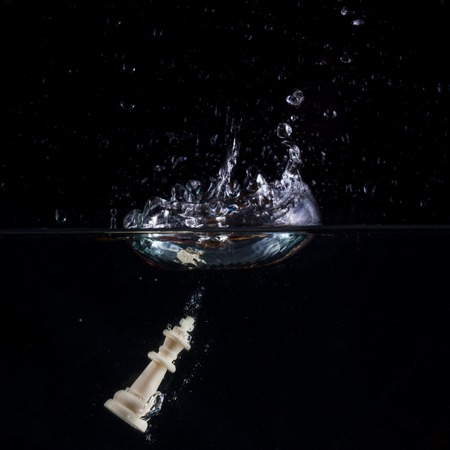 chess king fallen into the water on a dark background beautiful splash on the surface of the concept of business and board gamesの写真素材