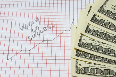 step growth graph drawn in pencil on a piece of paper and the inscription in English the way to success is a fan of one hundred dollar bills the concept of business and earningsの写真素材