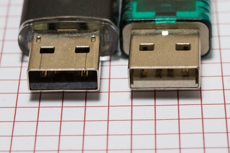 metal edges of two different flash drives on a sheet of paper close up concept of information...
