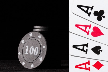 black poker chips on a dark background and a bright combination of four aces the concept of gambling...