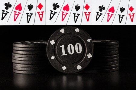 columns of black poker chips on a dark background and combinations of four aces casino concept