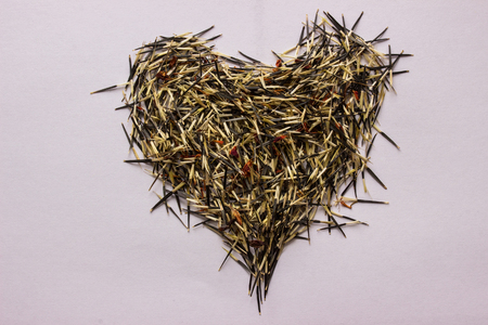 heart laid out of marigold seeds on a paper background close up concept of nature and gardeningの写真素材