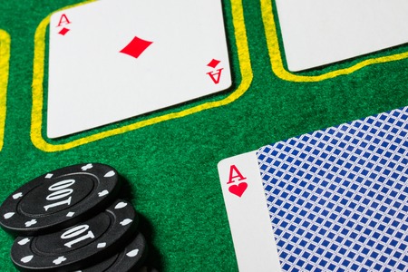 playing cards on a green poker canvas next to it are black chips business and casino concept