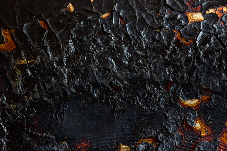 black texture of burnt and cracked metal on the surface of the frying pan close-up exciting patterns grunge background for designの写真素材