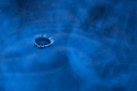 small shiny drop explosion on the surface in a mystical blue mist concept of natural elementsの写真素材