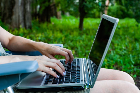 girl sitting in nature with laptop on her lap. High quality photoの写真素材