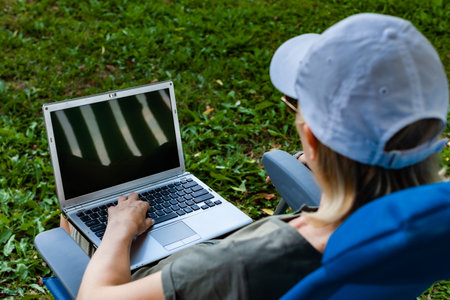 girl sitting in nature with laptop on her lap. High quality photoの写真素材