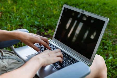 laptop lying on the lap of a woman on the keyboard which she presses with her fingers. High quality photoの写真素材