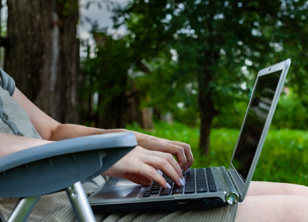 laptop lying on the lap of a woman on the keyboard which she presses with her fingers. High quality photoの写真素材