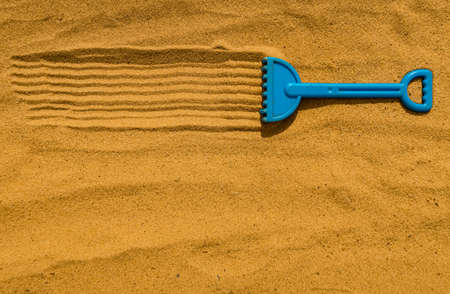 children's little rake lying in the sandbox on the sandの写真素材
