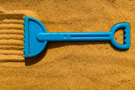 children's plastic rake lying on the yellow sandの写真素材