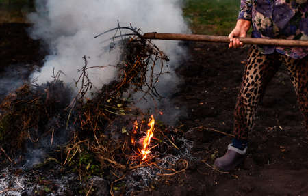 burning branches and tops that a man with a pitchfork moves. High quality photoの写真素材