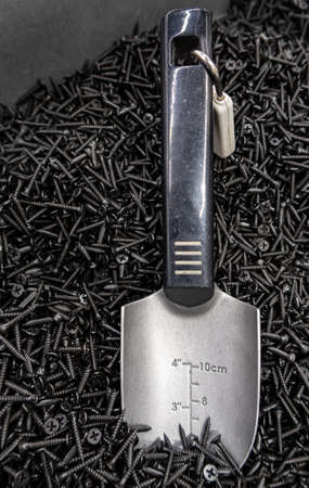 a lot of self-tapping screws in a box with a scoop. High quality photoの写真素材